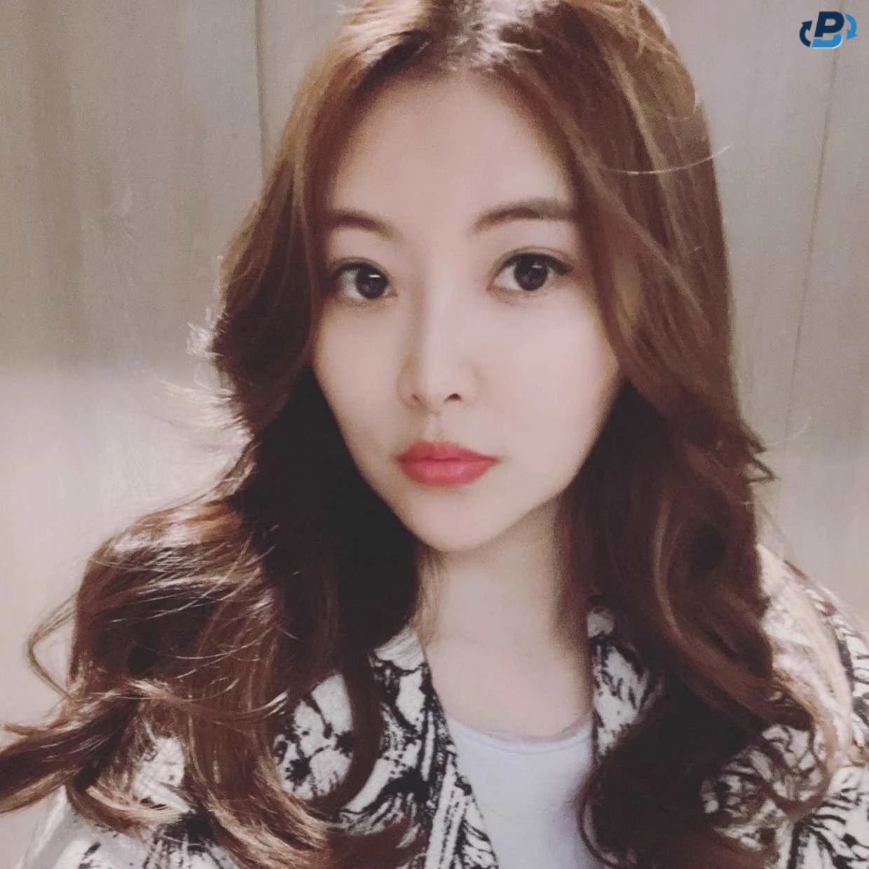Selfie of an Asian woman of indeterminate age and with hauntingly beautiful almond eyes, long brown hair, red lips, and porcelain skin
