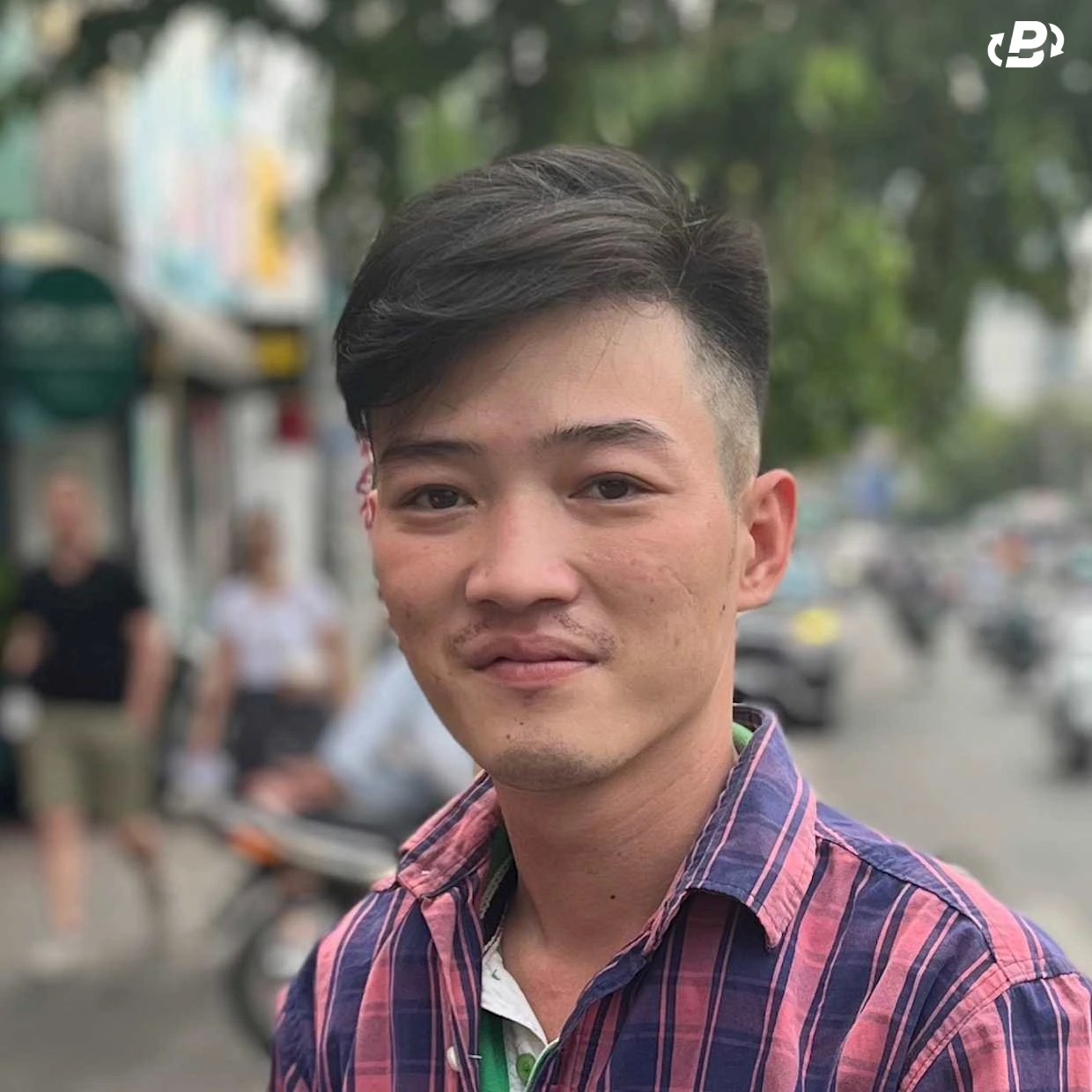 Close-up of a young man, his cheeks pocked and his lips contorted into a grimace that indicates he is hiding lot of pain that